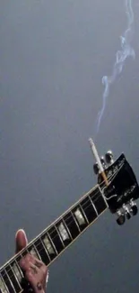 Close-up of guitar with smoke rising on a gray background.