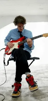 Guitarist on chair in minimalist white room with electric guitar.