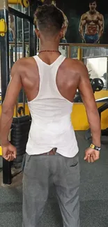 Person in gym wearing tank top training with equipment.