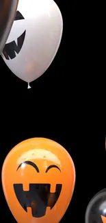 Halloween-themed balloons with jack-o'-lantern faces on a black background.