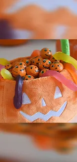 Halloween plush pumpkin with candy and gummy decorations.