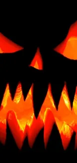 Spooky Halloween pumpkin face with glowing eyes and sharp teeth on black background.