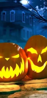 Halloween pumpkins glowing at night with a spooky house in the background.