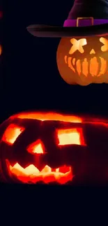 Glowing jack-o'-lanterns with witch hat in a dark Halloween setting.