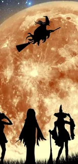 Silhouette of witches with a full orange moon in the background.