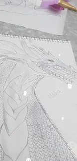 Black and white dragon sketch with intricate details on paper.