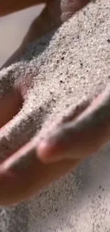 Sand flowing gently through a person's fingers.