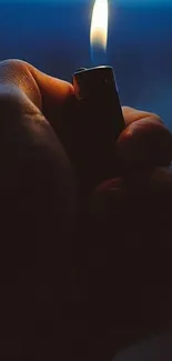 Hand holding a lit lighter in the dark.