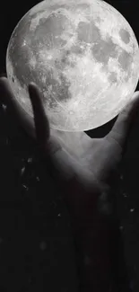 Hand gracefully holding the luminous moon in a dark night sky.