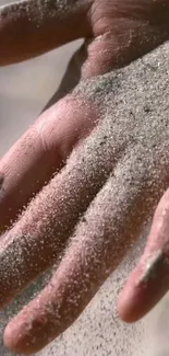 Close-up of a hand covered in soft sand texture.