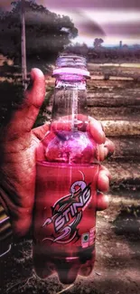 Hand holding a pink energy drink bottle outdoors.