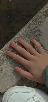 Hand resting on urban pavement with shoe.