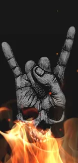 Hand gesture with skull and flames on dark background.