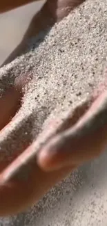 Hand letting sand fall softly through fingers, creating a peaceful texture.