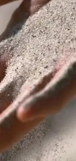 A close-up of a hand gently sifting through fine sand.