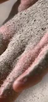 Close-up of a hand with fine sand grains for a calming mobile wallpaper.