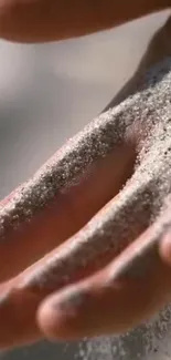 Close-up of sand gently falling on a hand's skin.