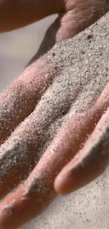 Close-up of a hand gently holding sand.