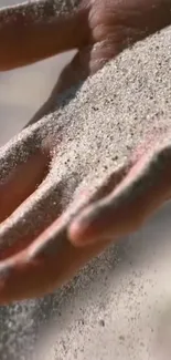 Close-up of a hand holding fine sand, creating a calming and natural texture.