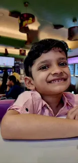 Child smiling indoors with colorful decor.