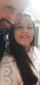 Cheerful couple taking a selfie indoors with a gift box in hand.