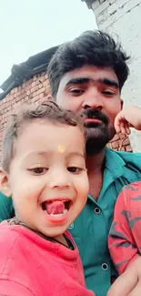 Father and children smiling outdoors with brick background.