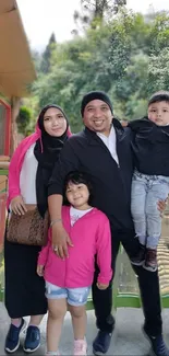 Family smiling in front of a scenic outdoor backdrop.