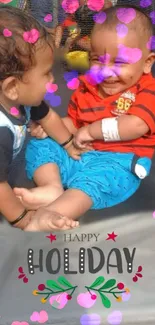 Two toddlers smiling with 'Happy Holiday' text and heart accents.