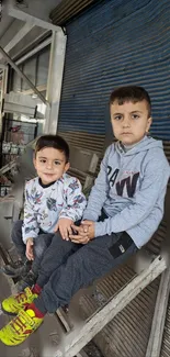 Two kids sitting in an urban setting, showcasing playful energy.