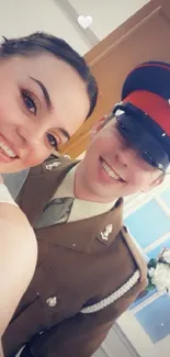 Smiling pair in uniform, bright setting.