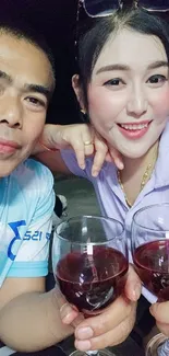 Two friends smiling and toasting with wine glasses.