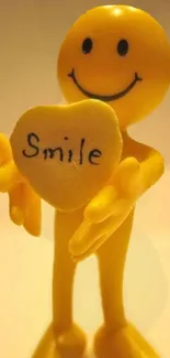 A cheerful yellow smiley holding a heart with 'Smile' written on it.