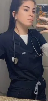 Healthcare worker taking a mirror selfie in navy blue scrubs.