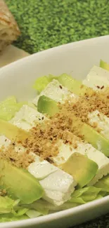 Avocado and feta salad in a white bowl with sliced bread.