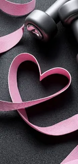 Pink ribbon heart with dumbbells on black background.