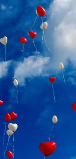 Heart-shaped balloons floating in a blue sky with clouds.