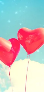 Two red heart-shaped balloons float against a blue sky.