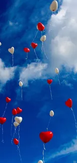 Red and white heart balloons float in a vibrant blue sky with fluffy clouds.