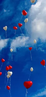 Heart-shaped balloons float in a blue sky with clouds.