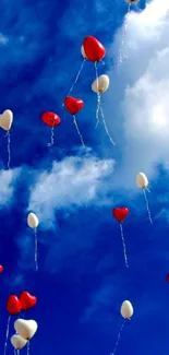 Heart-shaped balloons floating against a vivid blue sky with clouds.