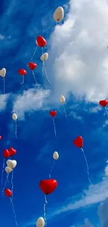 Heart-shaped balloons floating in blue sky with clouds.