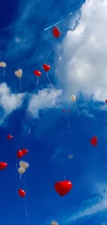 Red and white heart balloons floating in a bright blue sky with clouds.