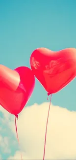 Two red heart-shaped balloons float in a sunny blue sky.