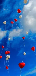 Heart balloons floating in a clear blue sky with white clouds.