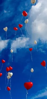 Red and white heart balloons floating in a vibrant blue sky.