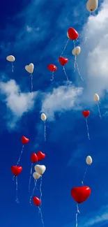 Heart-shaped balloons floating in a vibrant blue sky.