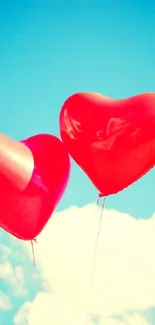 Two heart-shaped balloons float in a blue sky.