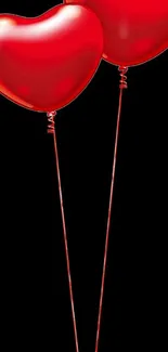 Two red heart-shaped balloons on black background.