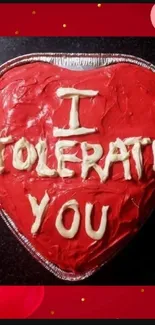 Heart-shaped cake with 'I Tolerate You' message on a mobile wallpaper.