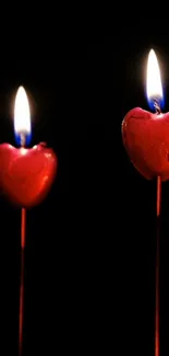 Heart-shaped candles glowing in darkness.